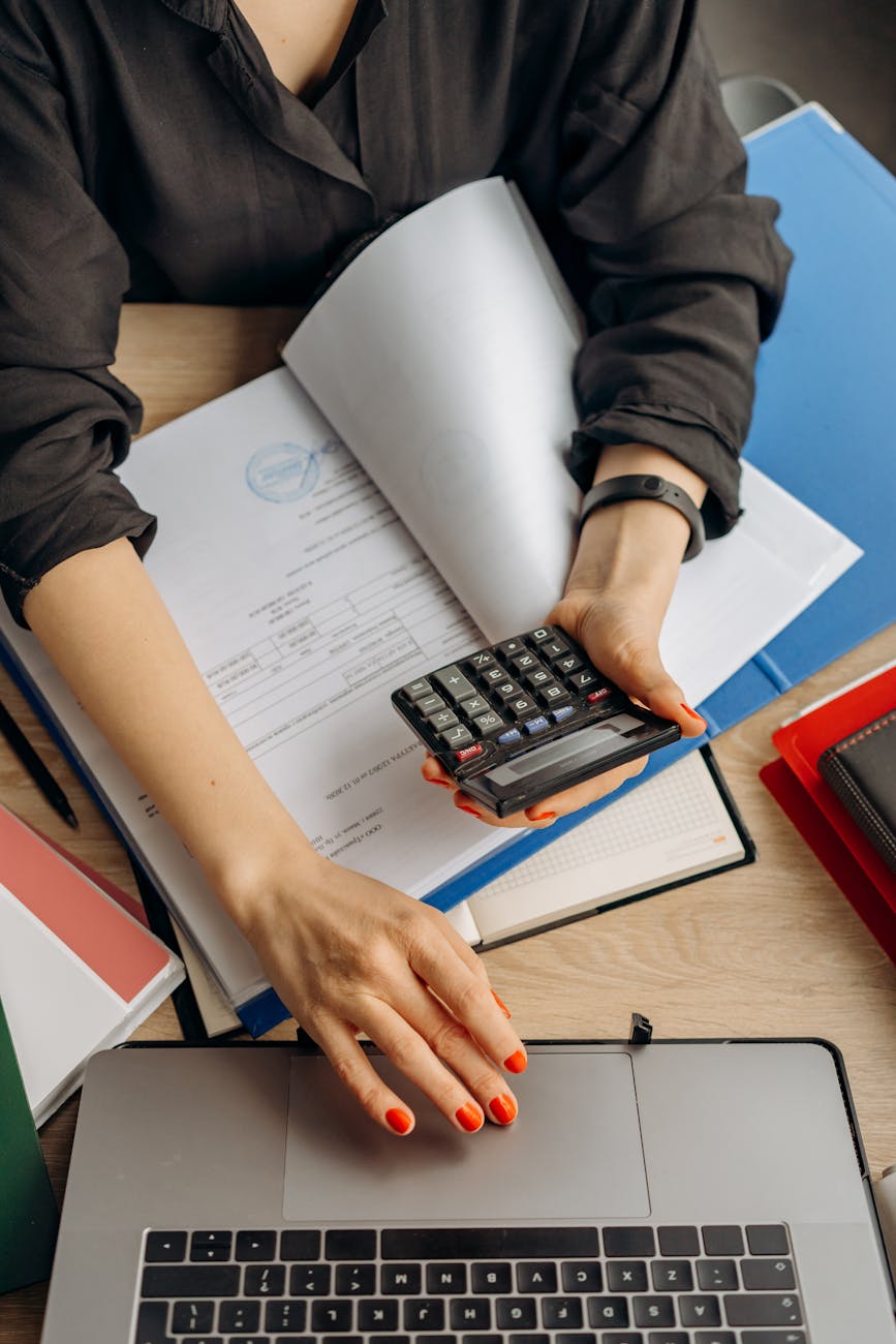 person holding black calculator while using laptop